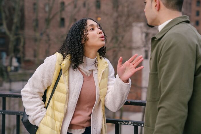 Mujer explicando trucos vitales a un hombre en conversación casual al aire libre en un día frío de otoño.