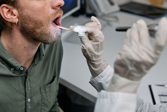 Hombre realizando prueba genética con hisopo en boca, explorando genes buenos o malos en estudio médico.