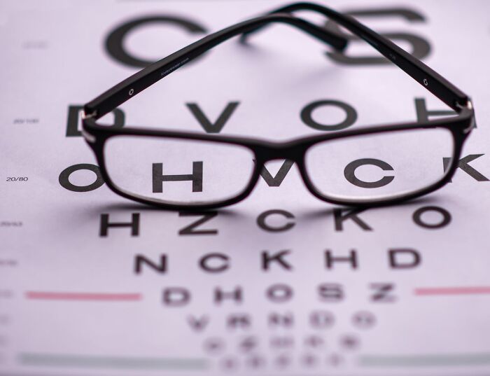 Gafas enfocadas en una tabla optométrica, ilustrando la importancia de los genes en la salud visual.
