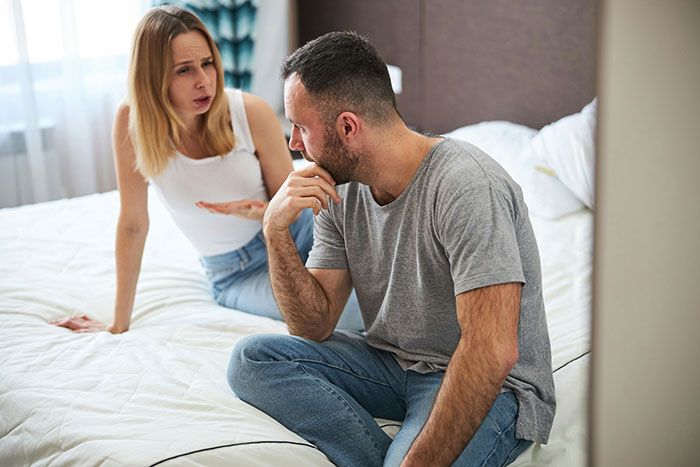 Pareja discutiendo en la cama mostrando señales de infidelidad y tensión emocional en una relación conflictiva.