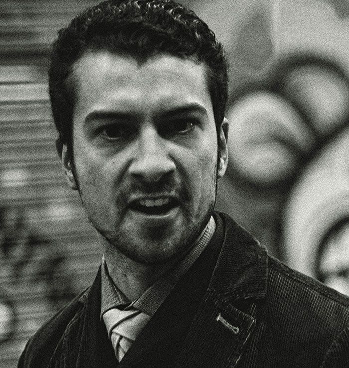 Hombre con expresión de enojo señalando señales de infidelidad en una imagen en blanco y negro urbana.