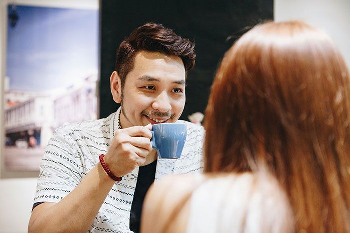 Hombre sonriente tomando café en una cita, mostrando señales de infidelidad que la gente ignoró.