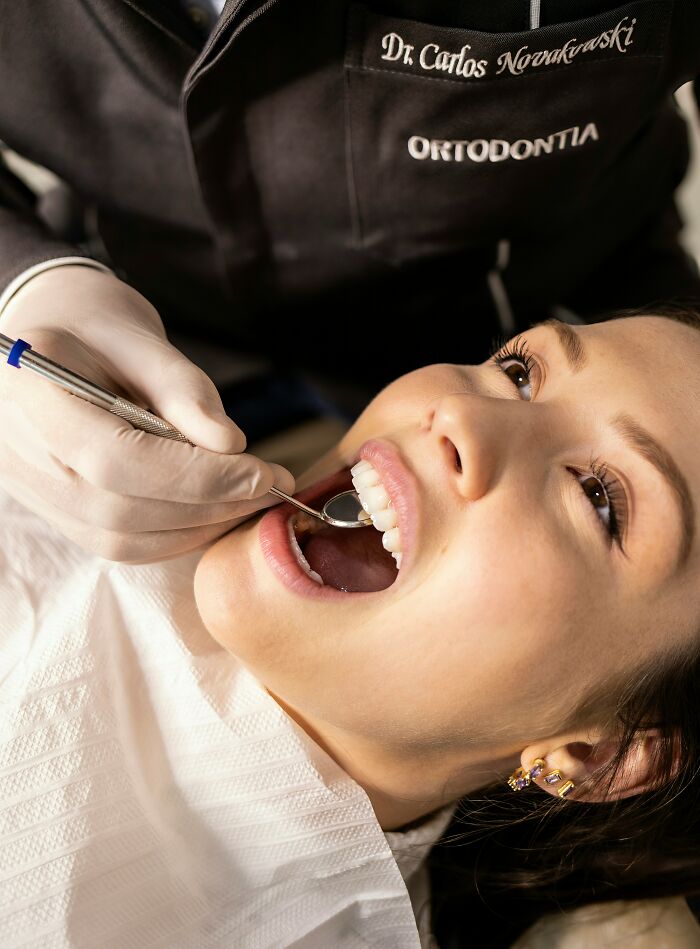 Paciente recibiendo revisión dental con especialista en ortodoncia, mostrando sonrisa y dientes cuidados, genética única.