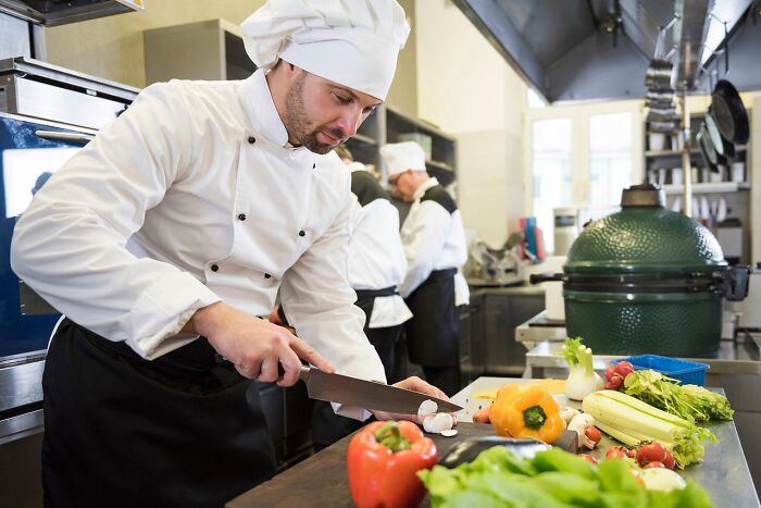 Chef en cocina profesional usando trucos vitales para preparar verduras frescas en su día a día.