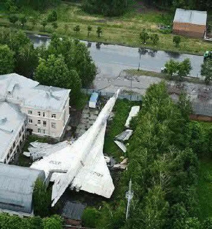 Avión abandonado entre árboles y edificios, uno de los lugares misteriosos encontrados en Google Earth desde el aire.