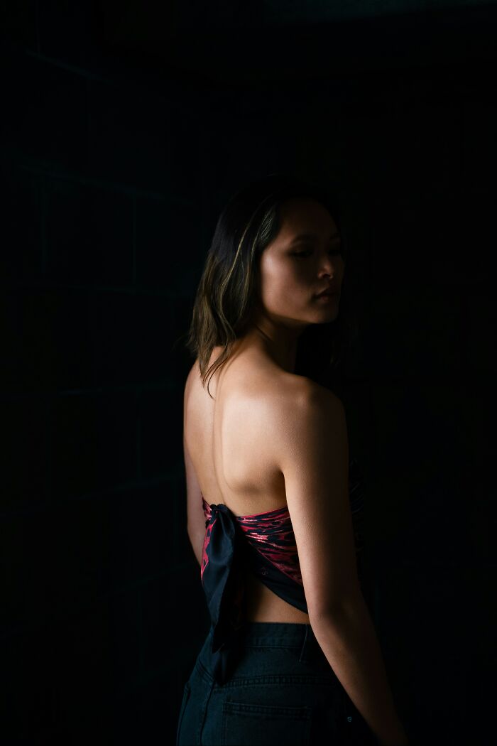 Mujer con lote genética única, de espaldas, en iluminación baja mostrando rasgos distintivos y belleza natural.