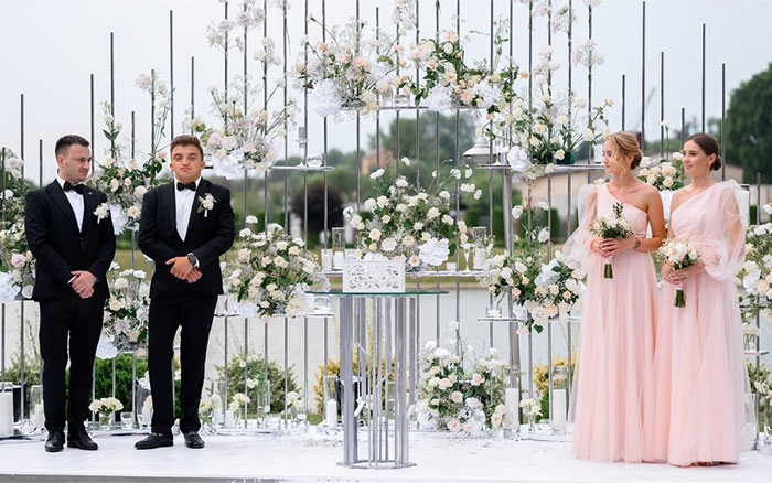 Pareja y damas de honor en boda elegante con decoración floral blanca y ambiente al aire libre, historias de bodas inesperadas.