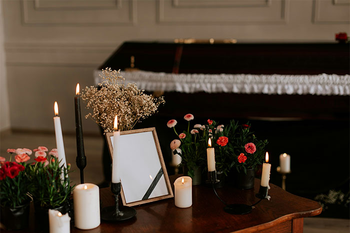 Velas encendidas y flores sobre mesa de madera frente a un piano en una escena relacionada con historias de bodas desafortunadas.