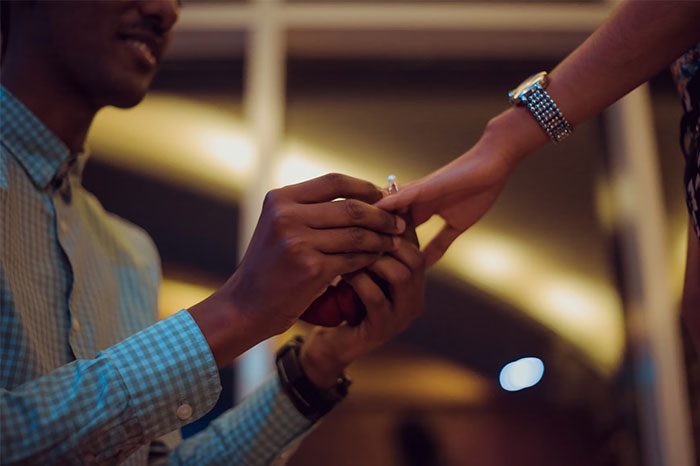 Hombre colocando un anillo de compromiso a una mujer en un momento íntimo durante una boda con historias que fueron de mal en peor.