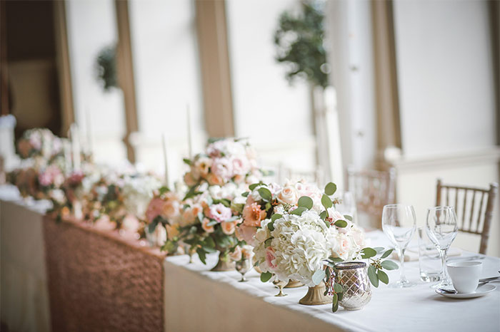 Arreglo floral en mesa de boda con copas y vajilla en salón elegante antes de historias de bodas que fueron de mal en peor.