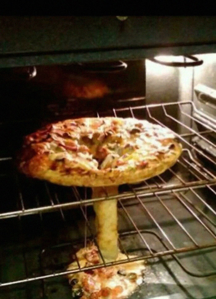 Pizza en horno con un queso derritiéndose que crea una imagen confusa y divertida sin contexto claro.
