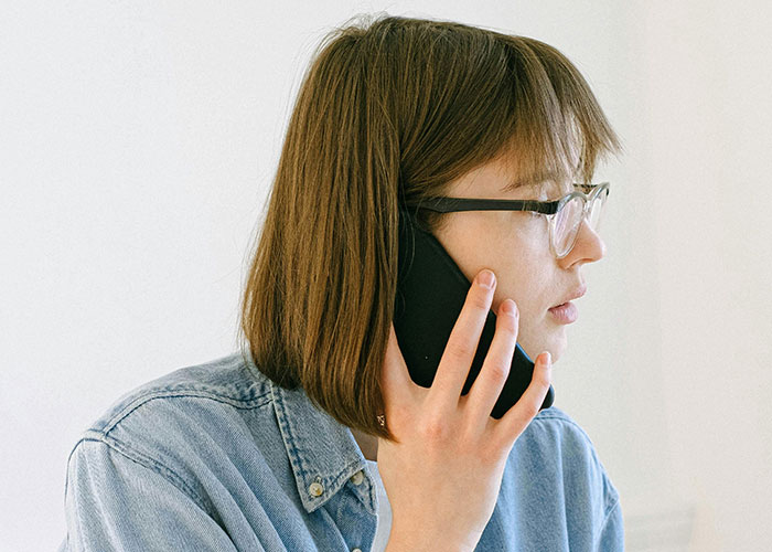 Mujer con gafas hablando por teléfono, ilustrando citas terribles contadas por camareros que las presenciaron.
