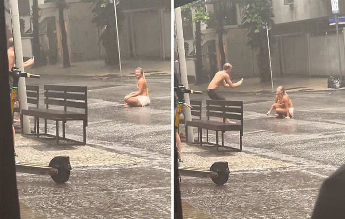 Influencers vergonzosos posando bajo la lluvia en la calle sin importar el sentido común ni la moral cerca de un banco.