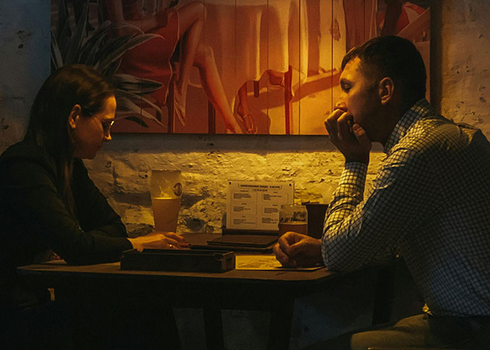 Pareja en una cita en restaurante con ambiente tenue, representando escenas de citas terribles según camareros.