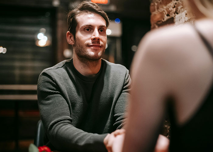 Pareja en cita en restaurante, hombre visiblemente inseguro, escena que refleja citas terribles contadas por camareros.