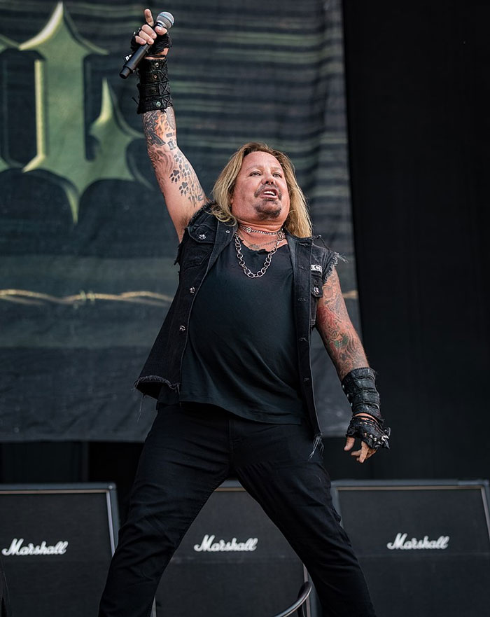 Cantante de rock con tatuajes en concierto, ejemplo de celebridades que hicieron algo horrible olvidado por el público.