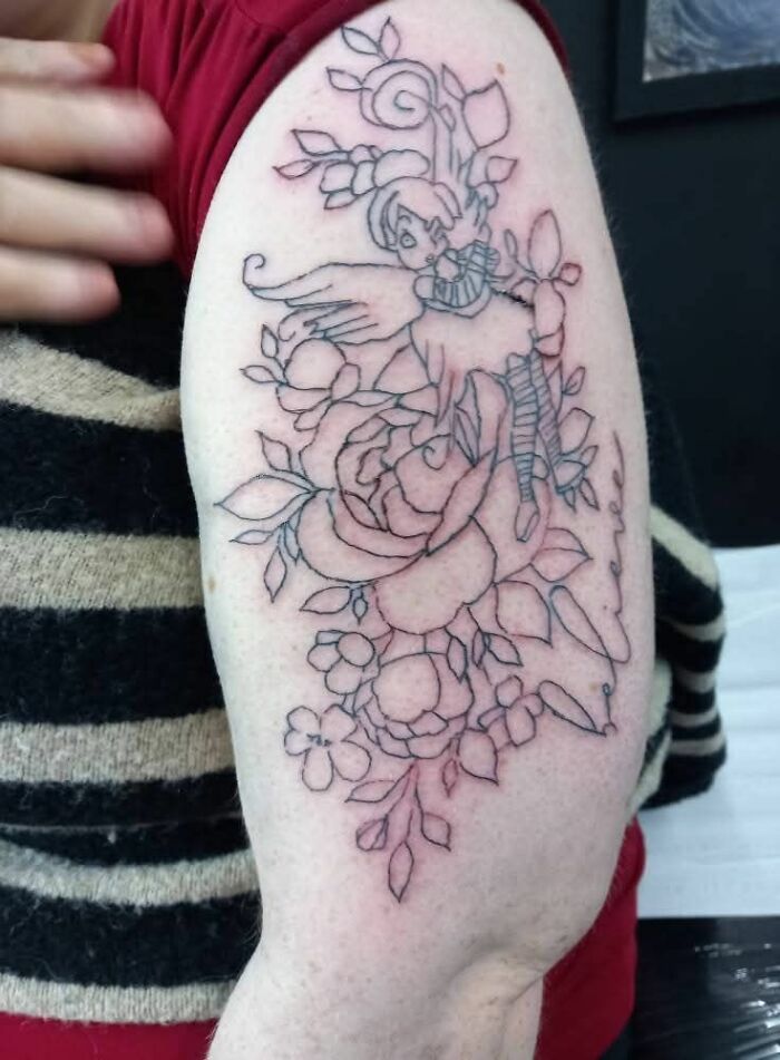 Tatuaje en brazo con diseño de flores y hada, ejemplo de tatuajes horribles que muestran errores difíciles de borrar.