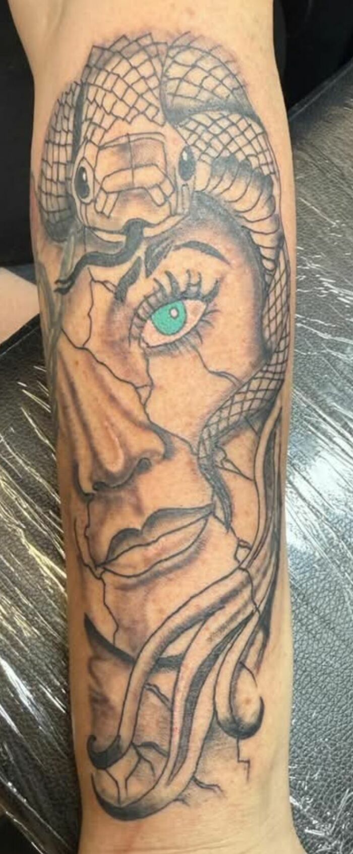 Tatuaje de rostro femenino con serpiente de escamas enredada, ejemplo de tatuajes horribles difíciles de borrar.