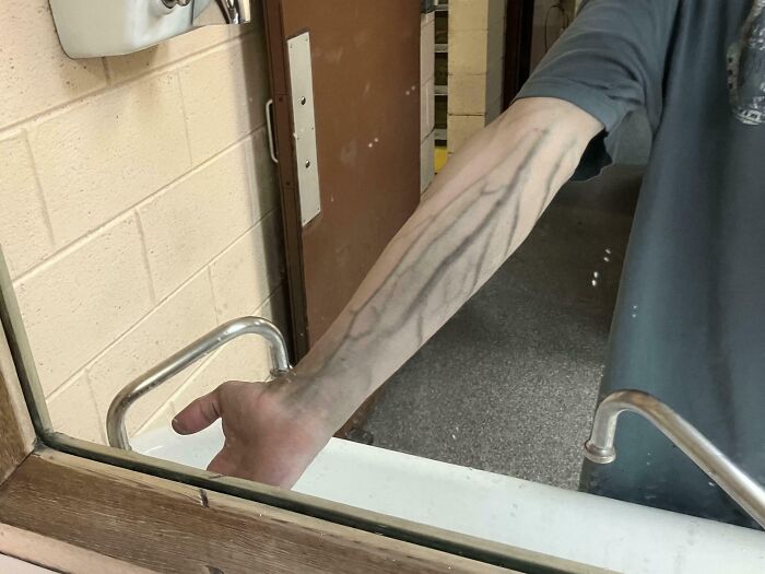 Brazo con venas muy marcadas y visibles reflejado en un espejo, imagen curiosa del cuerpo humano.