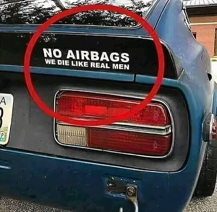 Parte trasera de un coche azul con calcomanía humorística sobre hombres y seguridad que toca razones por las que las mujeres viven más.
