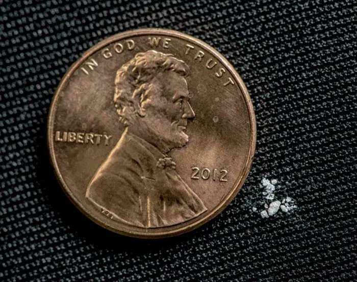 Moneda de un centavo junto a pequeñas piedras blancas sobre tela oscura en imágenes aterradoras e inquietantes.