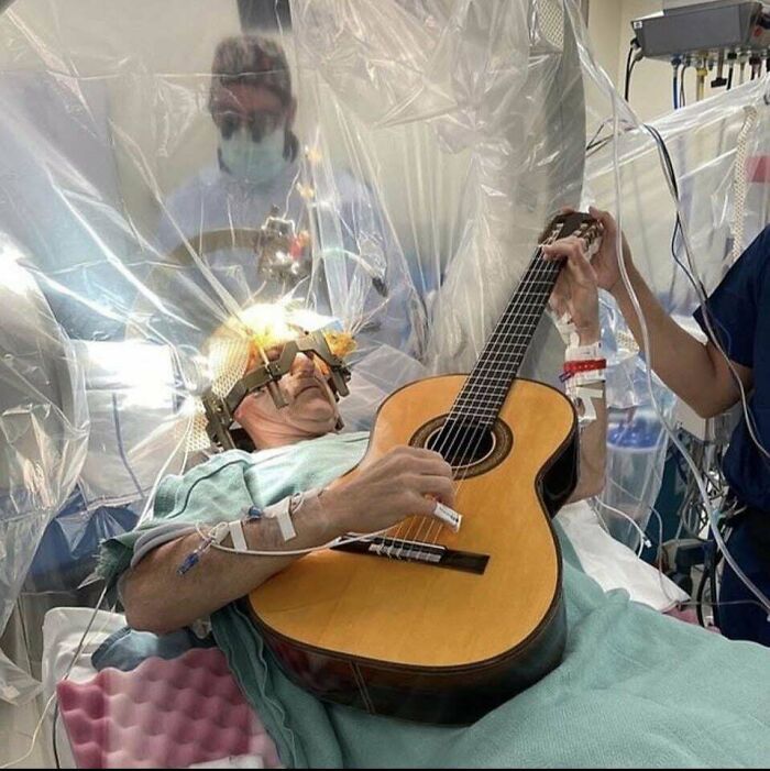 Hombre en cirugía cerebral tocando guitarra, imagen aterradora y inquietante en un entorno médico hospitalario.