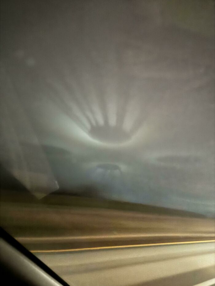 Sombra confusa y divertida en el parabrisas que parece una mano, imagen con efecto visual inusual y curioso.