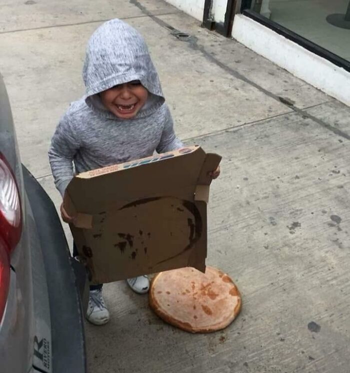 Niño con sudadera gris triste al dejar caer una pizza en el suelo en una imagen de padres teniendo un día peor.