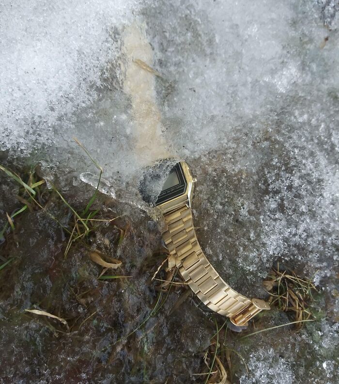 Reloj dorado parcialmente cubierto por hielo y nieve, ilustrando un día difícil para padres y madres.