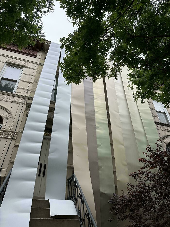 Personas confundidas con largas tiras de papel colgadas frente a una casa, pidiendo ayuda en Internet.