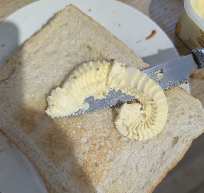 Mantequilla en forma de oruga sobre una rebanada de pan, mostrando objetos interesantes que parecen otras cosas.