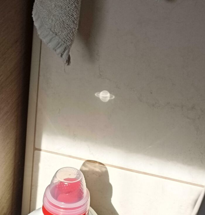 Reflejo de un vaso con agua que crea un objeto interesante que parece otro con forma de planeta Saturno.