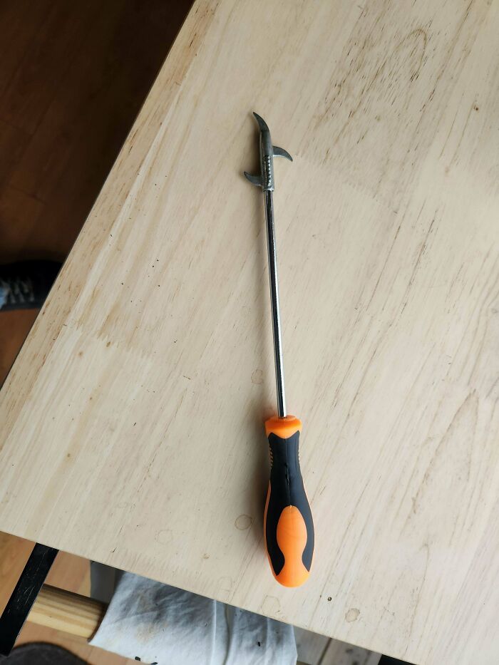 Herramienta metálica con mango negro y naranja, objeto extraño que confunde a personas que no saben qué es.