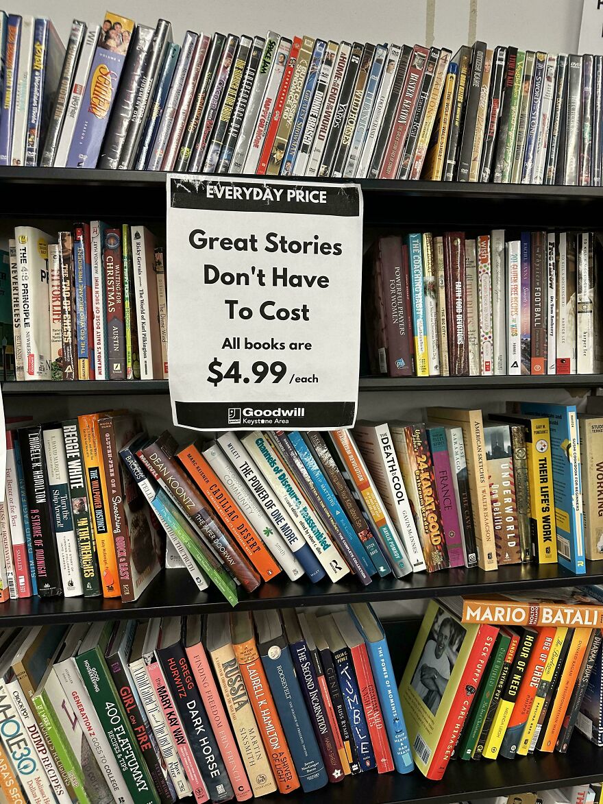 Estante con libros usados y señal que indica precios bajos, destacando la oferta de comprar libros nuevos baratos ahora.