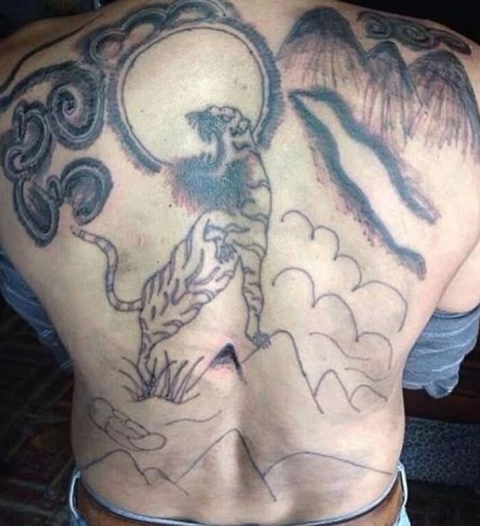 Tatuaje malo en espalda con tigre y elementos mal dibujados que muestran errores difíciles de borrar.