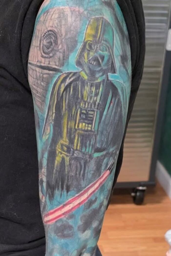 Tatuaje horroroso de Darth Vader con colores mal aplicados y diseño poco definido en brazo de persona.