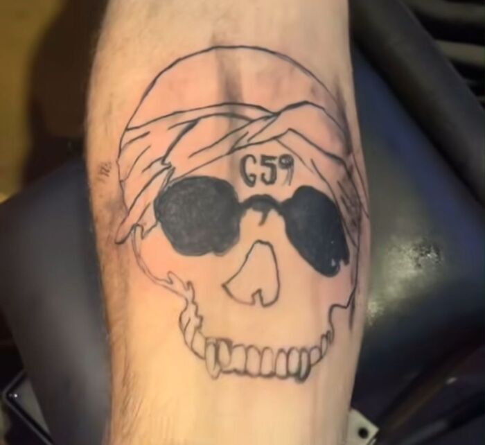 Tatuaje horrible de calavera con gafas oscuras y número 659, ejemplo de errores difíciles de borrar en la piel.