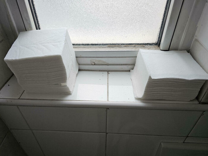 Pilas de servilletas mal apiladas en una ventana sucia de un lugar de trabajo tóxico y descuidado.