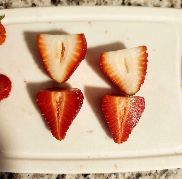 Imágenes comparativas de fresas cortadas mostrando diferencias en tamaño y color en una tabla blanca para nueva perspectiva visual.