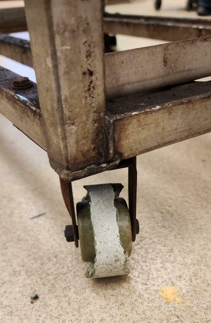 Rueda desgastada y rota en un lugar de trabajo tóxico mostrando condiciones peligrosas y deterioradas.