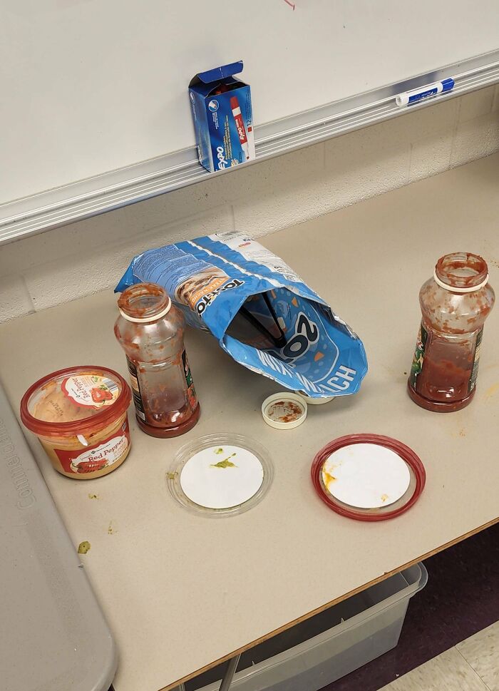 Mesa sucia en lugar de trabajo con restos de comida y botellas, ejemplo de un ambiente laboral tóxico y poco higiénico.