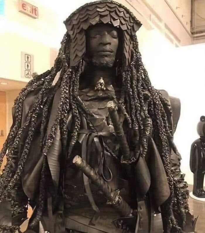 Escultura detallada de figura humana con trenzas y vestimenta tradicional, representando descubrimientos arqueológicos históricos.