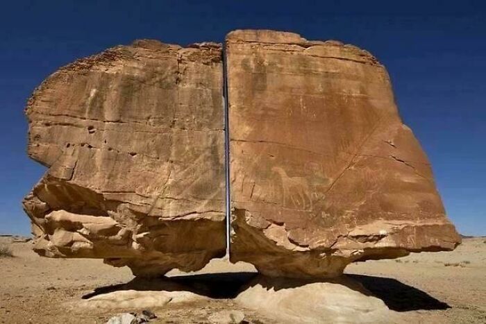 Roca gigante partida con pinturas rupestres, mostrando un misterio interesante que aún desconcierta a la gente en el desierto.