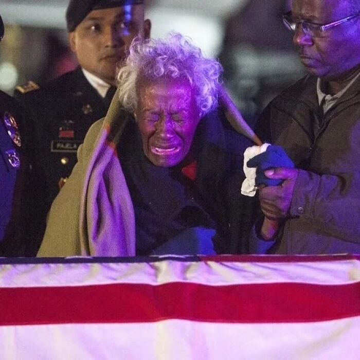 Mujer mayor llorando frente a una bandera, rodeada de personas, en una de las fotos históricas con curiosidades.