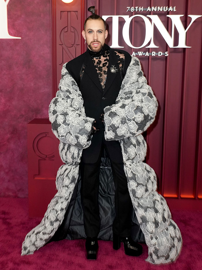 Hombre con abrigo floral y traje negro en la alfombra roja mostrando una de las malas decisiones de vestuario en los Premios Tony.