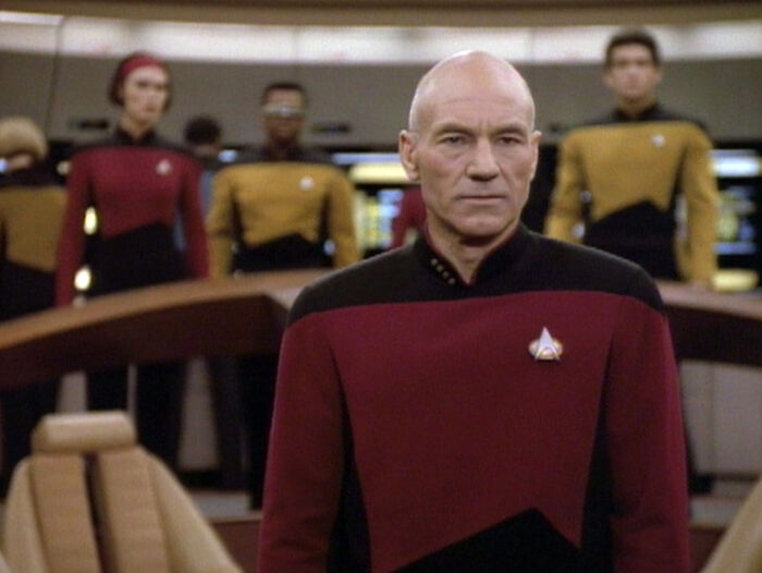 Capitán de Star Trek en puente de mando con tripulación al fondo en momento de error al corregir persona equivocada.