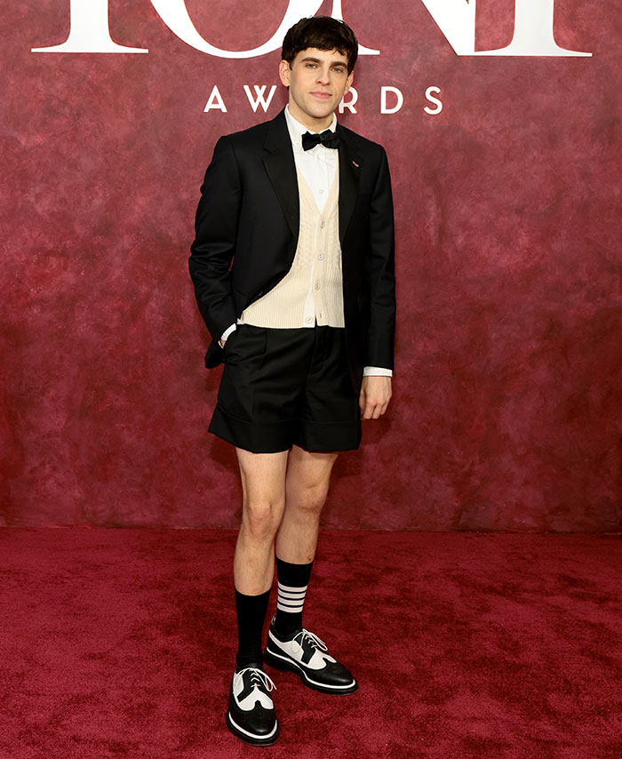 Joven en los Premios Tony con chaqueta formal, chaleco blanco y pantalones cortos negros, ejemplo de malas decisiones de vestuario.