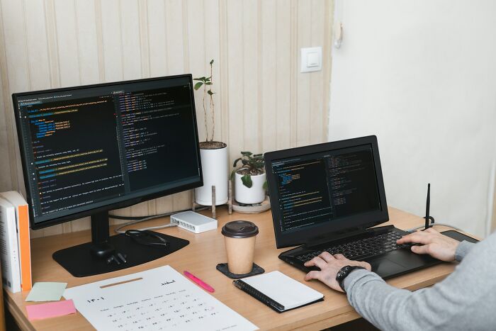 Persona equivocada intentando corregir código en computadora con fallos visibles en escritorio de trabajo moderno