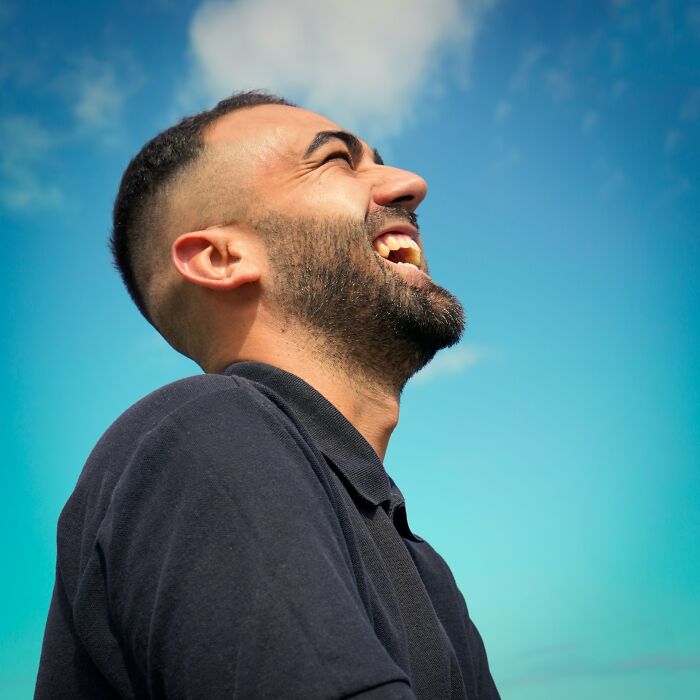 Hombre con barba riendo bajo el cielo azul, representando momentos en que se intentó corregir a la persona equivocada.