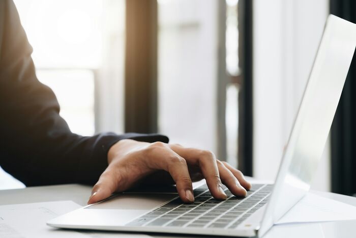 Persona escribiendo en laptop en un escritorio con luz natural, simbolizando experiencias online aterradoras compartidas.